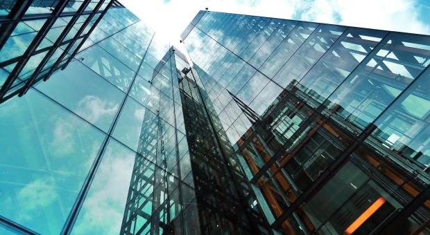 Looking up at a modern glass exterior of a skyscraper.